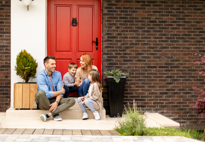 Happy Family in front of house Happy family outside their new home after working with a real estate agent in Pensacola.