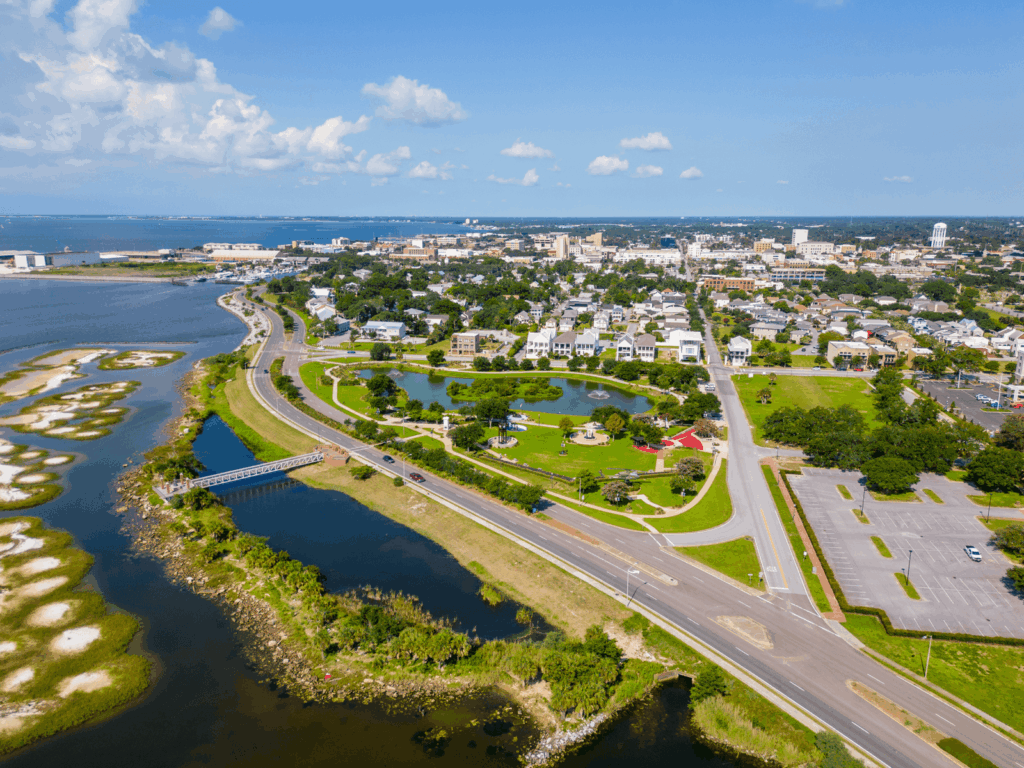 Aerial view of Pensacola waterfront park and cityscape with coastal roads, green spaces, and the bay, perfect for those who want to live in Pensacola.