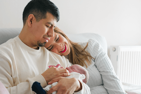 Happy young couple cuddling their newborn baby at home in Pensacola before deciding to sell their house.