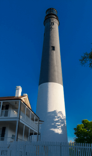 Pensacola Lighthouse standing tall with its black-and-white tower against a clear blue sky, located in Pensacola, Florida.